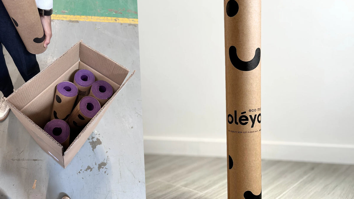 Open box of rolled purple mats in their kraft tubes at the warehouse, next to a close-up of the branded shipping tube