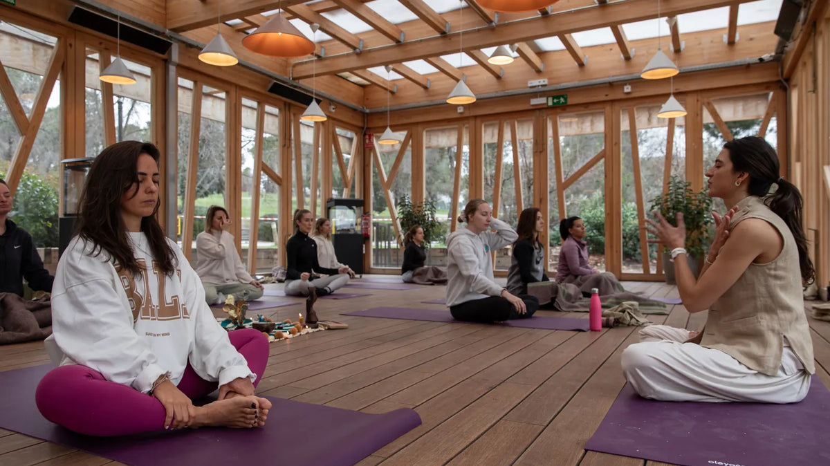 Group meditating on purple oléyoga mats in a wooden room