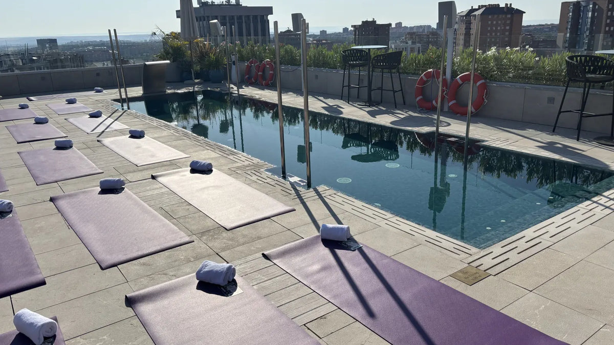Purple oléyoga mats laid out beside a rooftop pool