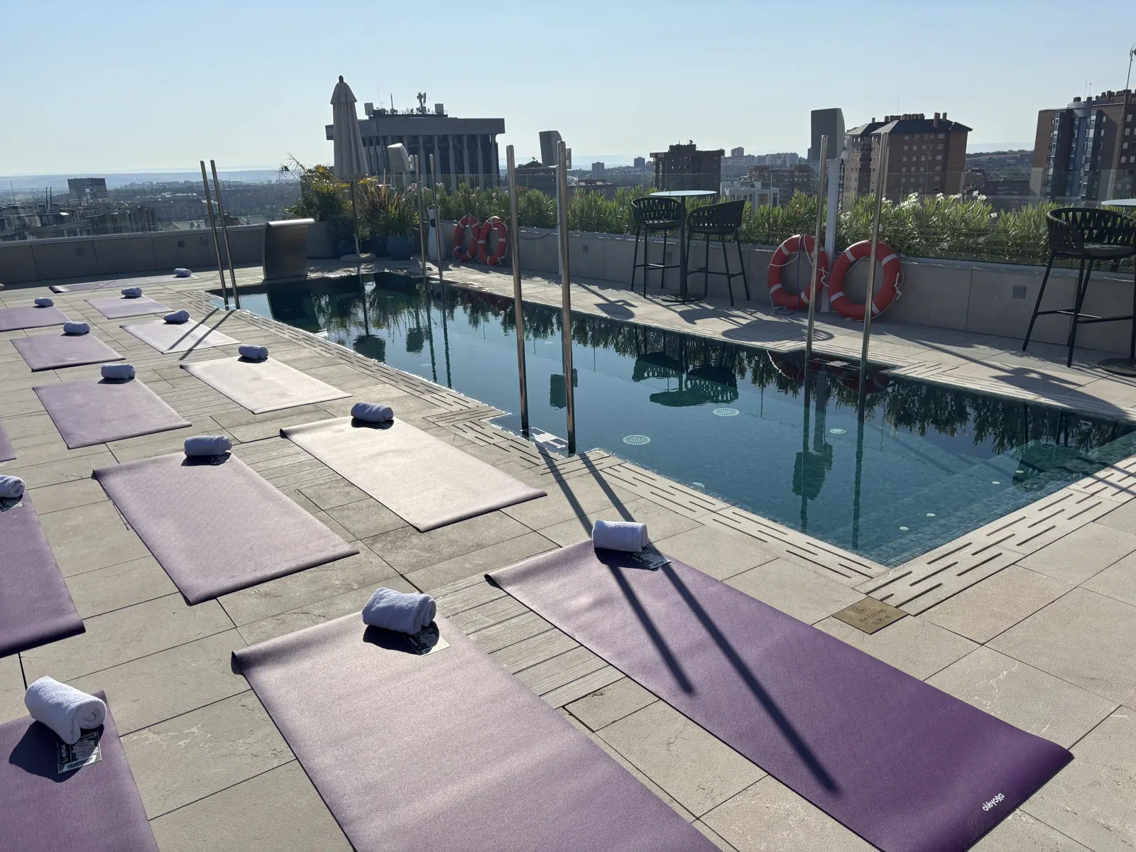 Purple oléyoga mats laid out beside a rooftop pool