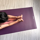Seated forward fold on the Deep Purple oléyoga Eco Daily yoga mat