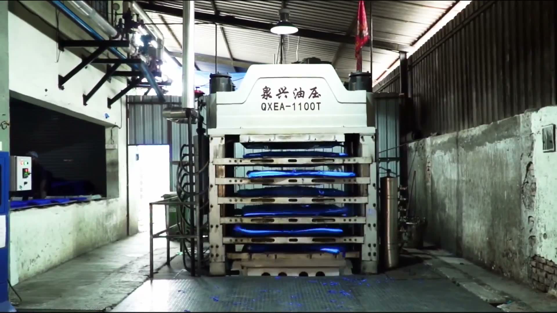 Factory hydraulic press compressing stacked blue yoga mat sheets