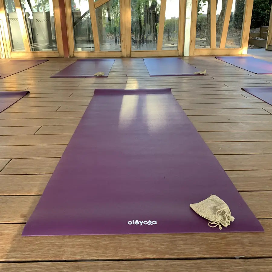 A yoga mat unrolled on a wooden floor in an empty room