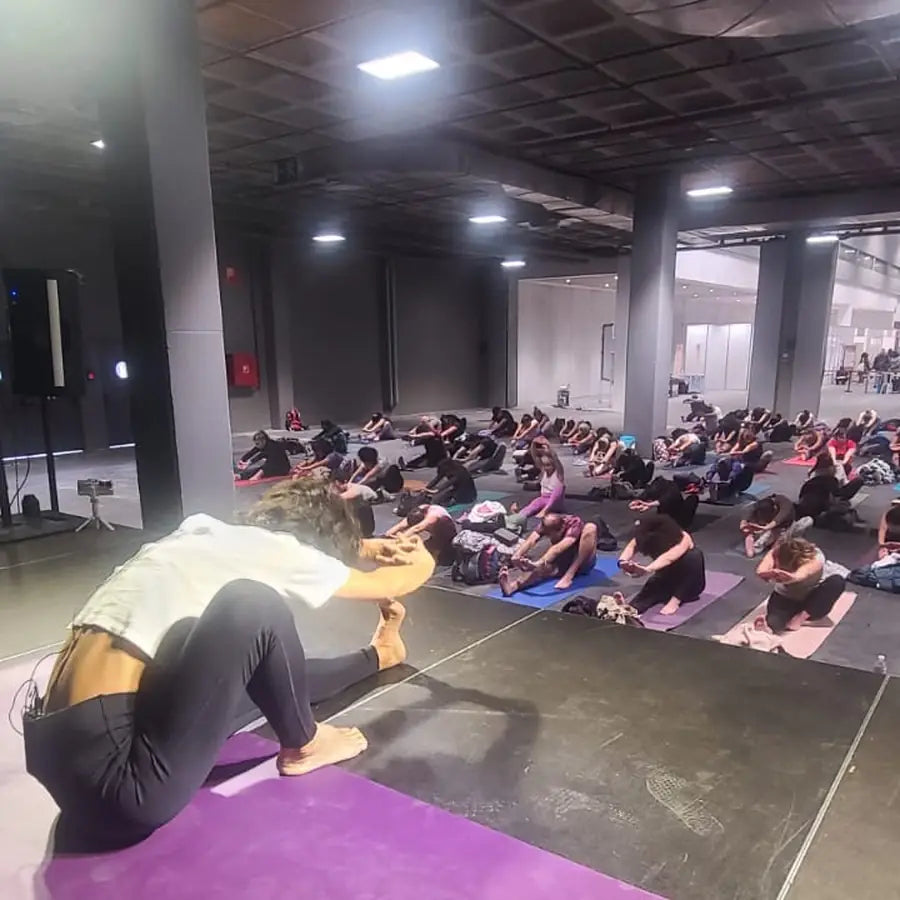 A large indoor yoga class practising on mats
