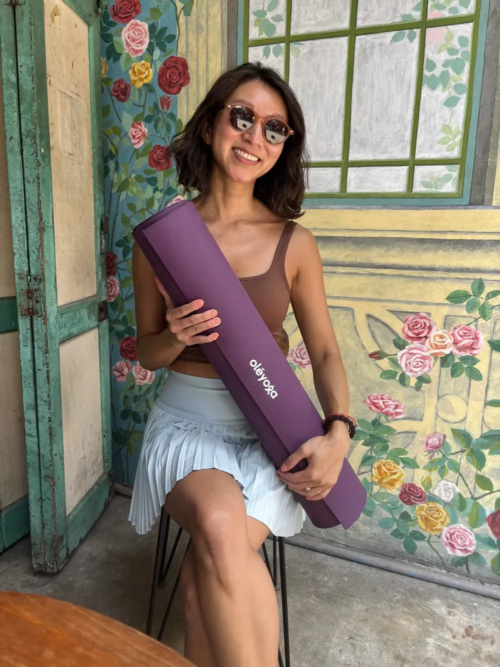 Smiling woman holding a rolled up oleyoga natural rubber yoga mat