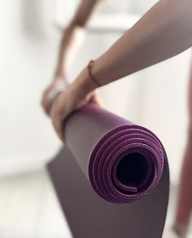 Manos sujetando una esterilla morada oléyoga enrollada